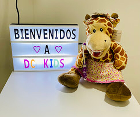 Letrero de "Bienvenidos a DC Kids" junto al títere de jirafa del consultorio